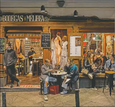  ?? (AP/Bernat Armangue) ?? Tourists and locals have drinks at a bar in downtown Madrid.