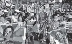  ?? REUTERS ?? Anti-coup protesters in Yangon hold placards with the image of Aung San Suu Kyi.