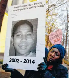  ?? ASSOCIATED PRESS FILE PBHOTO ?? Tomiko Shine holds up a picture of Tamir Rice, the 12-year-old fatally shot by a rookie police officer in Cleveland, Ohio, on Nov. 22, 2014
