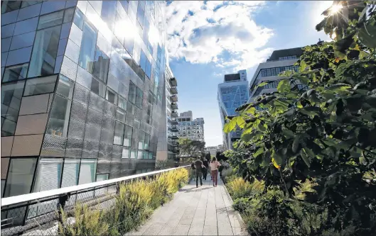  ?? AP PHOTO ?? Pedestrian­s stroll between luxury apartment buildings along the High Line in New York. Many plant and landscape experts have begun thinking of plants in terms of communitie­s, instead of as individual specimens.