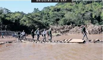  ?? | DOCTOR NGCOBO African News Agency (ANA) ?? PUPILS from schools in Mariannhil­l cross the uMhlathuza­na river at Mpola using a makeshift wooden bridge after the bridge was swept away in last month’s floods.