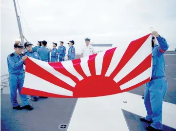  ?? — Reuters photo ?? Sailors fold the Japanese naval ensign after a flag lowering ceremony on the deck of Japanese helicopter carrier Kaga anchored near Jakarta Port ahead of its departure for naval drills in the Indian Ocean.