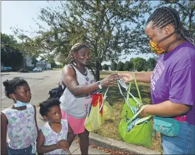  ?? JACK HANRAHAN — ERIE TIMES-NEWS VIA AP ?? Monique Jones, left, of Erie, receives a face mask Friday from Rajahnee Hollamon, a member of the Blue Coats, in the 900 block of East Eighth Street in Erie. A group of volunteers was canvassing the neighborho­od to educate residents about COVID-19.