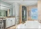  ?? ?? A jetted tub, a walk-in shower and a single-sink vanity with a makeup area highlight the primary bath.