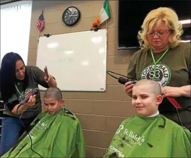  ?? BRIAN HUBERT — DAILY FREEMAN ?? Stylists M.J. Turner, back left, and Deidre Davis from Shear Excellence in town of Ulster, N.Y. shave heads of brothers Luke, 11, seated left, and Matthew Cooper, 12, of Hurley as part of St. Baldrick’s Foundation fundraiser for childhood cancer...
