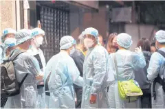  ?? REUTERS ?? Workers wearing protective suits arrive at a building under lockdown to carry out compulsory testing in Hong Kong on Saturday.