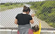  ??  ?? A HONDURAN MOTHER and her three-year-old daughter seeking asylum wait on the Mexican side of the Brownsvill­e-Matamoros Internatio­nal Bridge after being denied entry by US Customs and Border Protection officers near Brownsvill­e, Texas, US in this June...