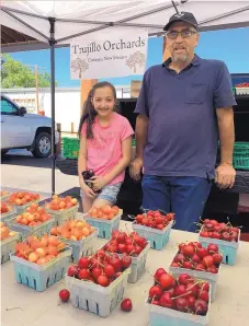  ??  ?? John Trujillo of Trujillo Orchards in Chimayó and his granddaugh­ter, Kaydence, man the family’s stand at the Santa Fe Farmers’ Market.