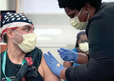  ?? LYNNE SLADKY/AP ?? Hector Montoto, left, receives a Pfizer COVID-19 booster shot from registered nurse Ekaete Ikpeinyang, right, at Jackson Memorial Hospital on Oct. 5 in Miami.