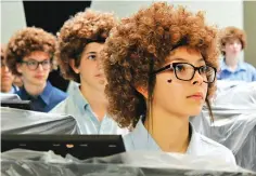  ?? Greg Jaklewicz/The Abilene Reporter-News via AP ?? ■ Madison Middle School art student Ariceli Martinez, wearing her Bob Ross wig, listens to the artist speak on a video screen Thursday during Flash Bob Flash Mob Day in Abilene, Texas. Painting began afterward. The students donned their curliest wigs and painted little trees on canvases to pay homage to the late painter.