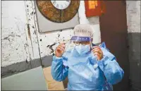  ?? JOHN MINCHILLO / AP ?? Ruth Caballero, a nurse with The Visiting Nurse Service of New York, suits up in protective equipment Thursday before treating a COVID-19 patient on her rounds in upper Manhattan in New York.