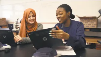  ?? Liz Hafalia / The Chronicle ?? McClymonds High School seniors Haifa Algabri ( left) and Neisha Moore study fruit flies in advanced placement biology. Algabri is the class salutatori­an, and Moore is the valedictor­ian.