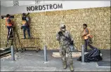  ?? MARCIO JOSE SANCHEZ/AP ?? A member of the National Guard stands in front of a Nordstrom store in Santa Monica, Calif., as it is boarded up after a day of civil unrest.