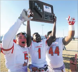  ?? JOSH HOLMBERG/ LAS VEGAS REVIEW-JOURNAL ?? Liberty football players Bryan Roland (1), Kaimi Batoon (5) and Alofania Tevaseu display the Patriots’ sixth consecutiv­e Sunrise Region championsh­ip plaque after defeating Basic 62-22 on Nov. 28, 2015. Liberty opens the season Friday by hosting Sunset Region runner-up Arbor View.