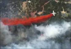  ?? JOHN WARK – FREELANCER, AP ?? AN AIRCRAFT LAYS DOWN A LINE of fire retardant between a wildfire and homes in the dry, densely wooded Black Forest area northeast of Colorado Springs, Colo., on June 13, 2013.