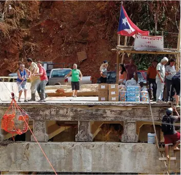  ?? PHOTO AFP ?? Des habitants du hameau de Rio Abajo sont complèteme­nt coupés du reste de l’île alors que le seul pont rejoignant la petite communauté a été détruit par l’ouragan.