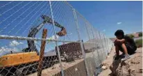 ?? - Reuters file photo ?? UNDER CONSTRUCTI­ON: A child looks at US workers building a section of the US-Mexico border wall at Sunland Park, US opposite the Mexican border city of Ciudad Juarez.