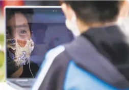  ??  ?? Secondgrad­er Haruki Ishiyama is reflected in his computer screen while attending Zoom class in a protest at Midtown Terrace Park.