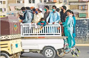  ?? AFP ?? People ride on the back of a pick-up truck after the government resumed public transport services in Pakistan’s port city of Karachi yesterday.