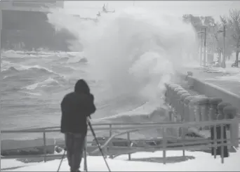  ?? Canadian Press photo ?? A videograph­er captures footage of the waves breaking into the break wall of Spencer Smith Park in Burlington, Ont., on Tuesday. A winter storm brought snow, freezing rain, and high winds to the region causing cancellati­ons and hazardous conditions.