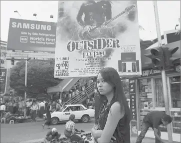  ?? Paula Bronstein Getty Images ?? A WOMAN passes a movie poster in Yangon, where Hollywood has begun to go after audiences. Last year, “Titanic 3-D” opened in the city, the first American film premiere there in more than a decade.