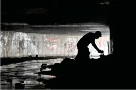  ?? (AP Photos/David Becker) ?? LEFT: Marlon offers some items to an individual during an outreach in the undergroun­d tunnels to provide counseling, food and water to the homeless living beneath the city in Las Vegas.