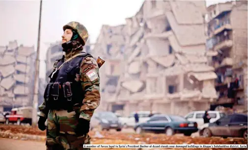  ??  ?? A member of forces loyal to Syria's President Bashar al-assad stands near damaged buildings in Aleppo's Salaheddin­e district, Syria