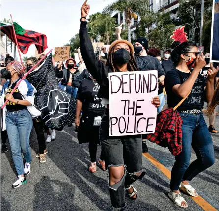  ?? ?? Left: BLM protesters in LA last year with a ‘Defund the Police’ placard
