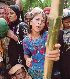  ?? [ FOTO REUTERS ] ?? Seorang gadis Rohingya keletihan kerana cuaca panas ketika menunggu bantuan kemanusiaa­n di kem sementara di Cox‘s Bazar, Bangladesh, semalam.