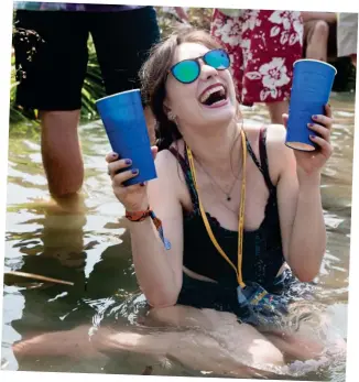  ??  ?? Take me to the river: A festival-goer cools off with drinks for two