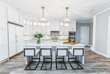  ?? Gracie Henley ?? Now, the kitchen in Brett and Jessica Calliers’ Seabrook home is a picture of contempora­ry design with white cabinets, quartz counters and stylish lighting.