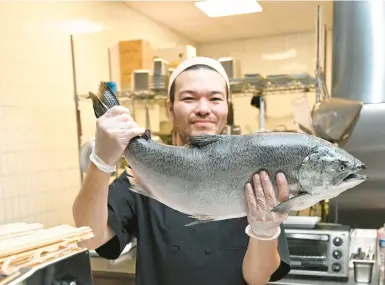  ?? AMY SHORTELL/MORNING CALL PHOTOS ?? Randevoo executive chef Greg Ioki holds up a salmon Thursday at the restaurant’s new location in Downtown Allentown Market. The restaurant, which began as a food truck, is expanding from its Bethlehem location.