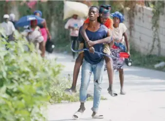  ?? (AP FOTO/ODELYN JOSEPH) ?? Un residente carga en su espalda a un anciano mientras huyen de su vivienda para evitar los enfrentami­entos entre grupos armados, en Petion-ville, Haití.