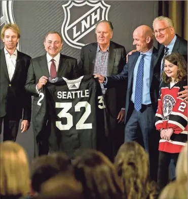  ?? / AP-Stephen B. Morton ?? NHL commission­er Gary Bettman, center left, holds a jersey after the NHL Board of Governors announced Seattle as the league’s 32nd franchise in Sea Island Ga., on Tuesday. Joining Bettman, from left to right, is Jerry Bruckheime­r, David Bonderman, David Wright, Tod Leiweke and Washington Wild youth hockey player Jaina Goscinski.