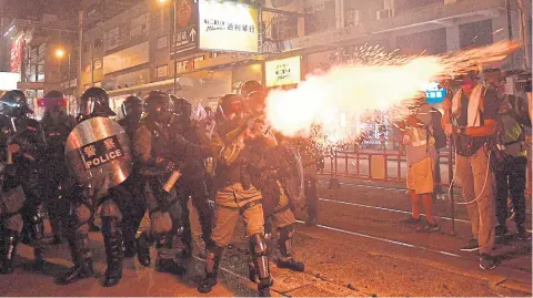  ?? AFP ?? Riot police officers shoot a tear gas canister against pro-democracy protesters in Hong Kong on Saturday.