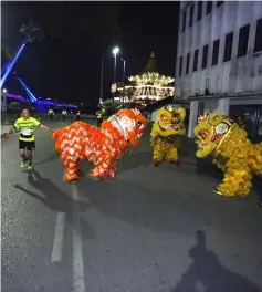  ??  ?? A runner touching the behind of a lion for good luck as a lion dance is performed near the old Courthouse.