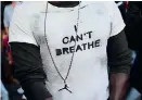  ??  ?? (Above) A protestor wears a T-shirt reading "I can't breathe" during a Black Lives Matter rally in France (AFP). (Right) Michelle Obama's VOTE necklace.