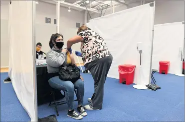  ?? PHOTOS BY AXEL KOESTER ?? Rachel Cetina, a preschool teacher’s aide in a Catholic school, receives a Moderna COVID-19 vaccine Monday during a clinic at Loyola Marymount University in Westcheste­r. The clinic was hosted by the Archdioces­e of Los Angeles.