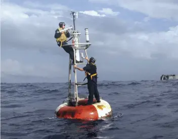  ??  ?? BELOW: Buoys can help gather data on weather conditions at sea. Here, members of the US Navy adjust an NOAA weather buoy