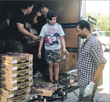  ?? Photograph­s by Vera Haller For The Times ?? VOLUNTEERS at CACI, a nonprofit in Montreal, unload supplies for a food bank that serves newly arrived asylum seekers. The nonprofit has seen demand for its services increase dramatical­ly in the last year.