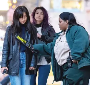  ?? TYLER PASCIAK LARIVIERE/SUN-TIMES ?? Millennium Park security officials wave a baton around a woman at a security checkpoint on April 21. Less than a week before, two teens were shot and at least 15 people were arrested during violence downtown.