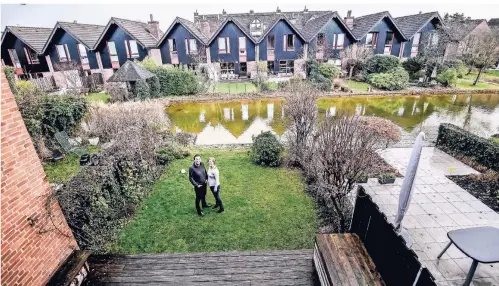  ??  ?? Ein Hauch von Holland: Gunilla Klinkhamme­r und Jörg Magar stehen in ihrem Garten, der an einer Gracht endet.