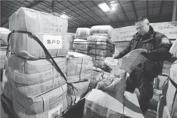  ?? RICHARD DREW/AP FILES ?? A U.S. border officer opens a shipment of counterfei­t Louis Vuitton bags in Kearny, N.J. The United States-Mexico-Canada Agreement requires all three countries to authorize their border guards to detain “ex-officio” — without a court order — pirated goods in transit to other nations. Canada is seen as a major in-transit point for such shipments.