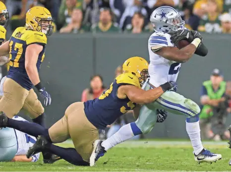  ?? MARK HOFFMAN / MILWAUKEE JOURNAL SENTINEL ?? Packers linebacker Nick Perry tackles Cowboys running back Ezekiel Elliott, who ran 28 times for 157 yards in Green Bay’s loss to Dallas on Oct. 19.