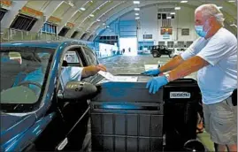  ?? LISA RATHKE/AP ?? A voter casts a ballot at a drive-thru voting station in the statewide primary in Barre, Vermont. States are looking at creative venues such as basketball arenas for in-person voting.