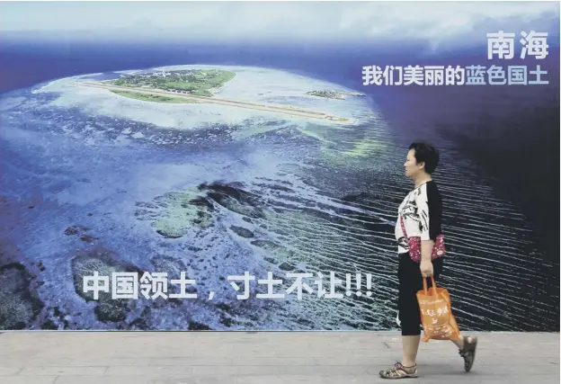  ??  ?? 0 A woman walks past a billboard that reads ‘South China Sea, our beautiful motherland, we won’t let go an inch’ in Weifang in east China’s Shandong province