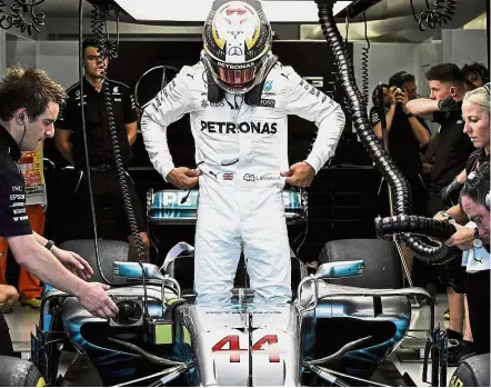  ??  ?? Unlucky car number?: Mercedes’ Lewis Hamilton preparing to get into his car ahead of the qualifying session of the Formula One Singapore Grand Prix yesterday. Hamilton will start from the fourth grid in today’s race. Below: Ferrari’s Sebastian Vettel...