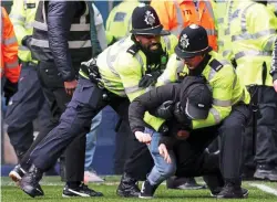  ?? ?? Unruly: a supporter is tackled as the violence continues