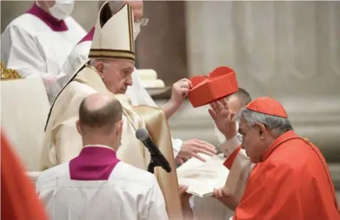  ?? FOTO AFP ?? Enrico Feroci krijgt zijn scharlaken­rode biretta (of bonnet) van paus Franciscus. Hij is een van de dertien kardinalen die het voorbije weekend door de paus gecreëerd werden.
