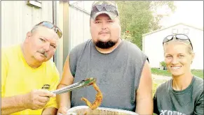  ?? PHOTO SUBMITTED BY DAN FULLER ?? Volunteers Don Akins, Chad Akins and Sophie Platter tempt youngsters with a batch of frog legs prepared at the Young Outdoorsme­n United Frog Gigging Party for area kids.